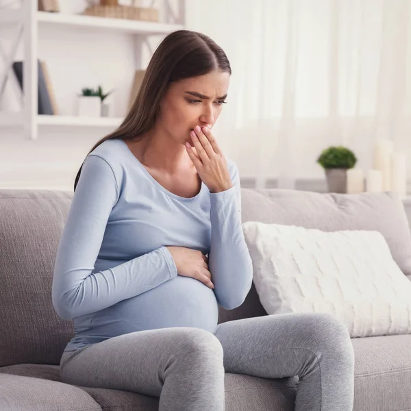 Kobieta w ciąży o ciąży Poranne nudności siedzi na kanapie — Zdjęcie stockowe