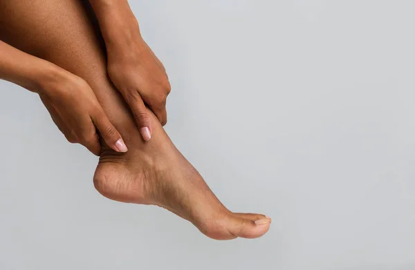 Close up of black woman massaging her ankle — Stock Photo, Image