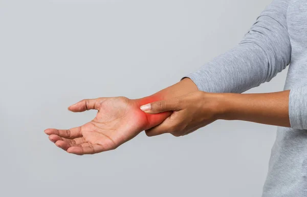 Female inflamed wrist over grey studio background — 스톡 사진