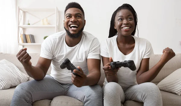 Joyful afro couple celebrating victory in video game