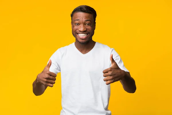 Millennial Guy Gesturing Polegares com ambas as mãos no estúdio — Fotografia de Stock