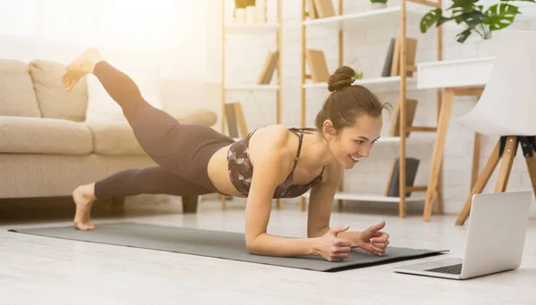 Mädchen trainieren zu Hause, machen Planken und schauen Videos auf dem Laptop — Stockfoto