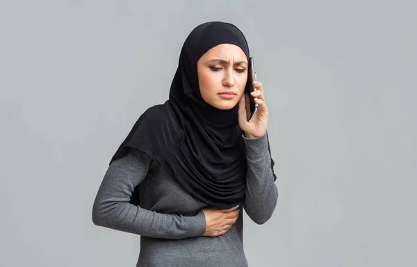 Sick muslim woman suffering from stomach pain, calling doctor for help — 스톡 사진