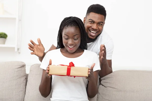 Ρομαντική έκπληξη. Χαρούμενη μαύρη κοπέλα που κρατάει δώρο από το στοργικό της αγόρι. — Φωτογραφία Αρχείου