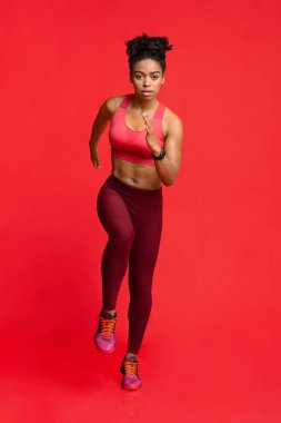 Kırmızı arkaplanda Afrika fitness modeli çalıştırılıyor