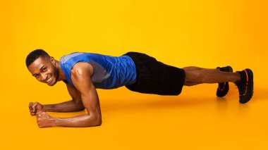 Formda bir afro sporcu, kalas çekirdek egzersizi yapıyor.