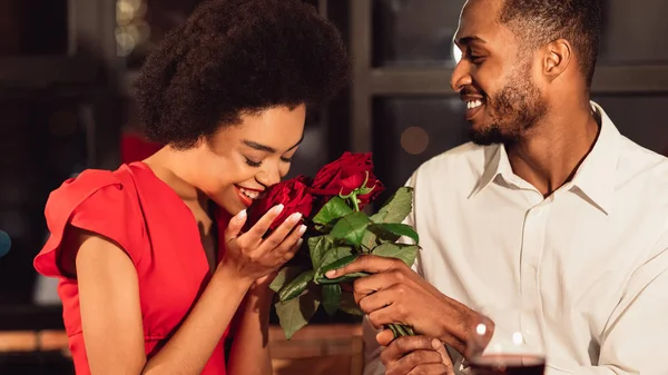 Девушка получает букет красных роз от бойфренда в ресторане — стоковое фото