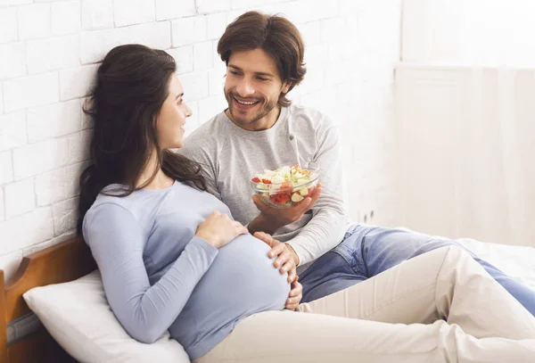 Amado marido dando salada de legumes frescos para sua esposa grávida — Fotografia de Stock