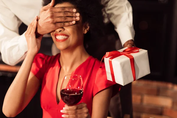 Guy giving regalo a fidanzata covering suo occhi in ristorante — Foto Stock