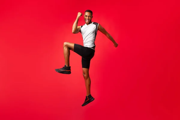 Full length afro ragazzo celebrando il successo saltando in studio — Foto Stock