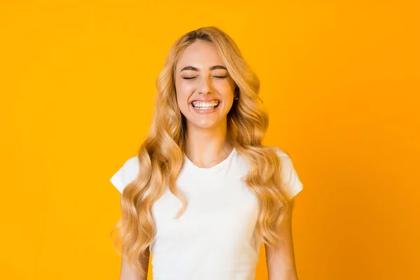 Funny girl laughing with closed eyes on yellow background — Stock Photo, Image