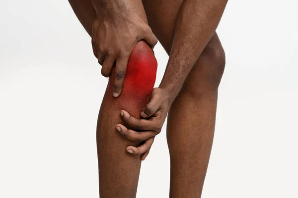Young man massaging his painful knee, close up — Stock Photo, Image