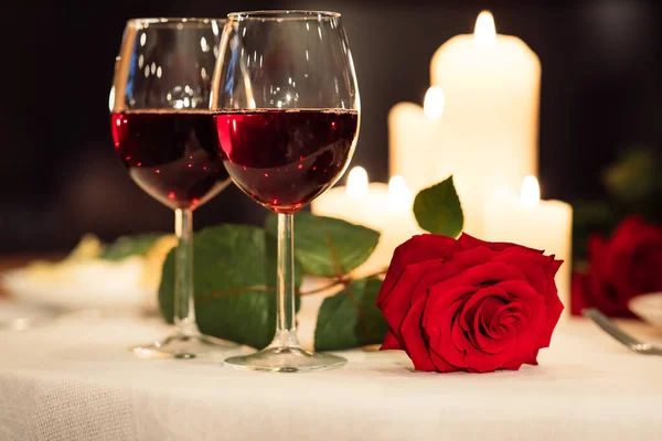 Dois copos de vinho tinto e rosa deitada na mesa do restaurante — Fotografia de Stock