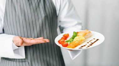 Aşçı sunar Balık Tabağı Mutfakta duruyor, Kırpılmış