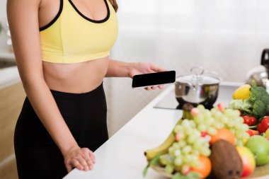 Mutfakta telefon kullanan, kalori hesaplayan bir kadın.