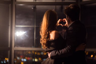 Sevgili çift ellerini kalbe bağlıyor.