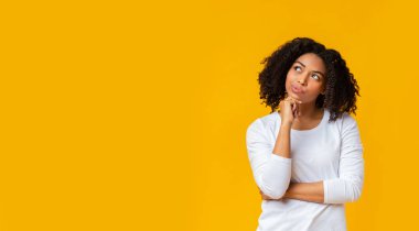 Doubtful afro girl thinking about something over yellow background clipart