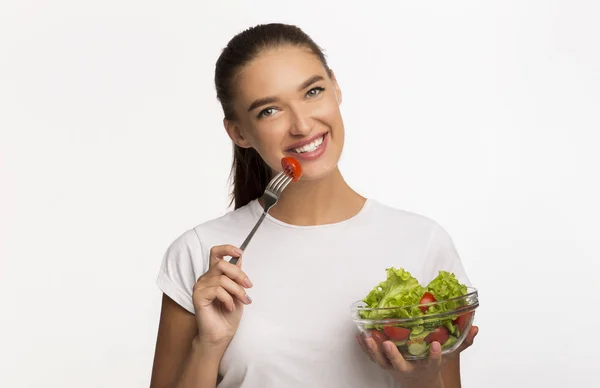 Positiv flicka äter Veggie sallad ler stående i studio — Stockfoto