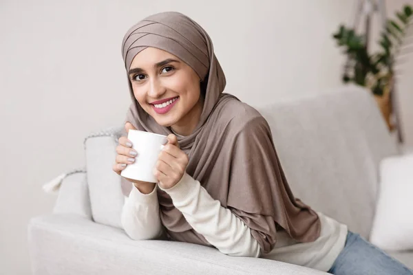Muslim gadis dalam hijab santai di rumah dengan secangkir kopi — Stok Foto