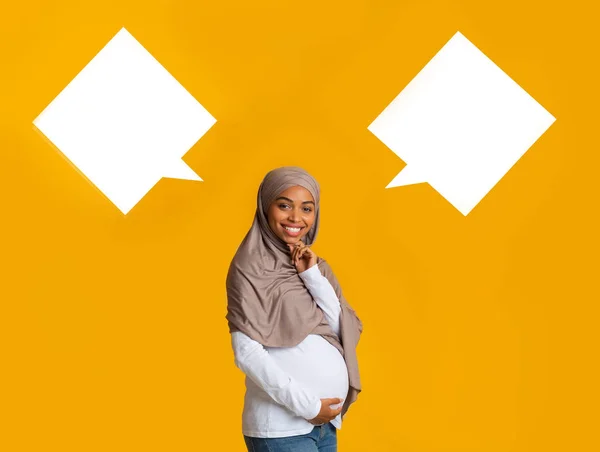 Pregnant afro muslim woman over background with two empty speech bubbles — 스톡 사진