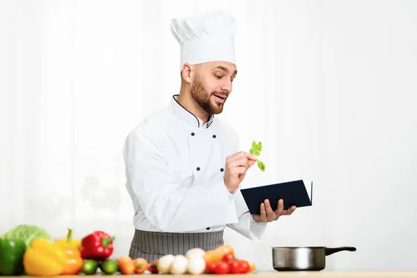 Chef Man leitura livro de receitas trabalhando na cozinha interior — Fotografia de Stock