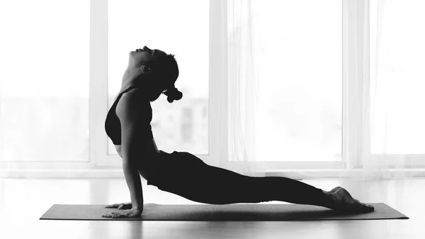 Fille faisant pose de yoga cobra sur le tapis, photo noir et blanc — Photo