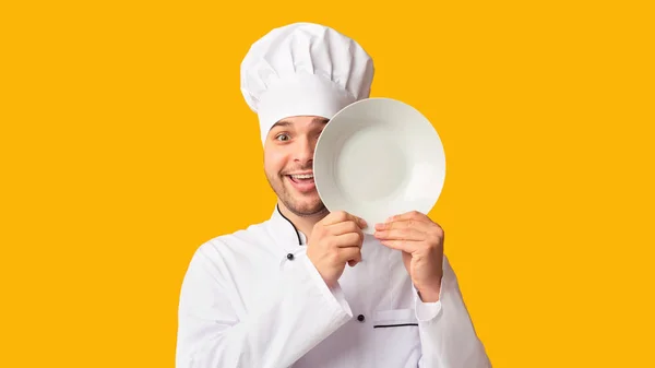 Lustige Koch Mann bedeckt Auge mit Teller über gelbem Hintergrund — Stockfoto