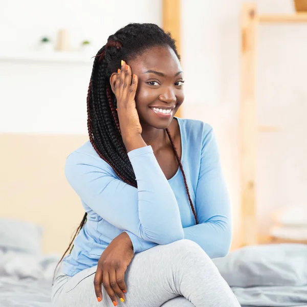 Afro-americana chica sonriendo en cámara posando sentado en cama —  Fotos de Stock