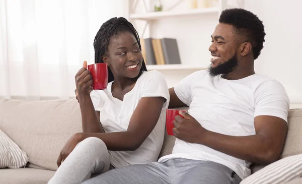 Fröhliches Afro-Paar entspannt bei Kaffee auf der heimischen Couch sitzend — Stockfoto