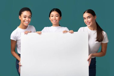 Three Women Holding White Poster Standing On Turquoise Background, Mockup