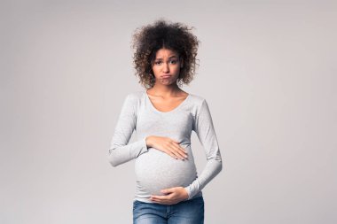 Hormonlar ve ruh hali değişiyor. Üzgün bir kadın göbeğine dokunuyor