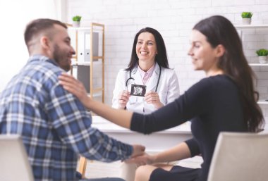 Happy couple enjoying pregnancy diagnosis in clinic
