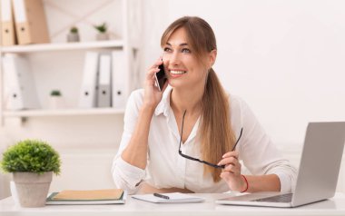 Joyful Entrepreneur Talking On Cellphone Sitting At Laptop In Office