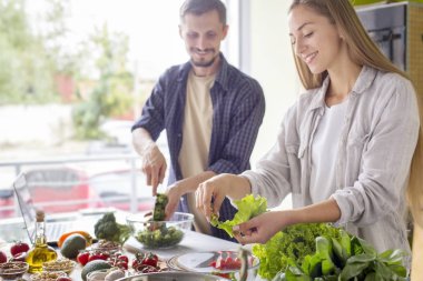 Handsome man and attractive young woman cooking together
