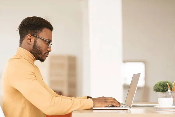 Afro kille arbetar på sin bärbara dator hemma — Stockfoto