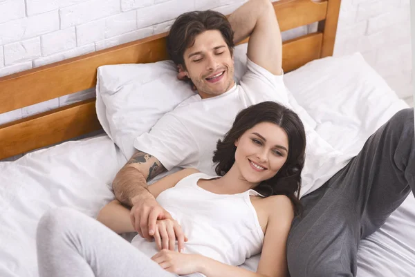 Счастливые супруги отдыхают в постели и наслаждаются близостью — стоковое фото