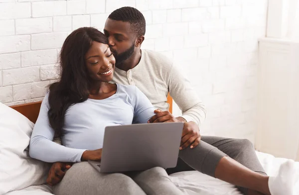 Zwanger meisje en haar man met behulp van laptop, liggend op bed — Stockfoto
