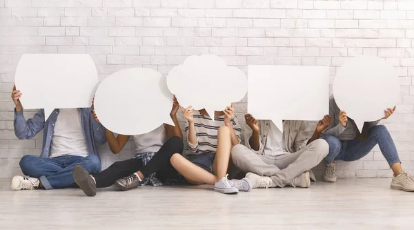 Students in casual clothes hiding behind speech bubbles — Stock Photo, Image