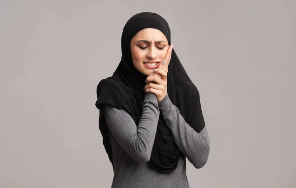 Szomorú muszlim nő hidzsábban, fogfájástól szenved, megérinti az arcát. — Stock Fotó