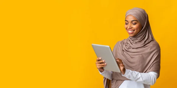 Sonriente chica negra islámica en hijab usando tableta digital —  Fotos de Stock