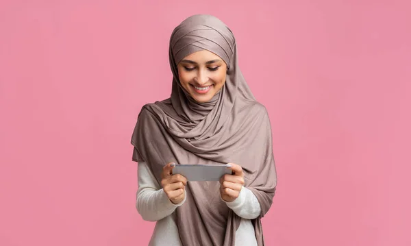 Μουσουλμάνα κοπέλα κρατώντας smartphone σε οριζόντιο προσανατολισμό, βλέποντας βίντεο — Φωτογραφία Αρχείου