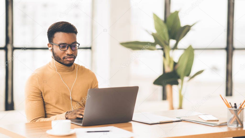 Concentrated afro guy in eyewear typing on keyboard