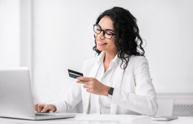 Smiling latin woman making purchases using computer