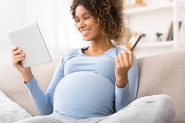 African-american expectant woman purchasing goods on tablet
