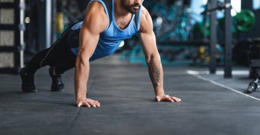 Sportsman making plank or push ups exercise at gym