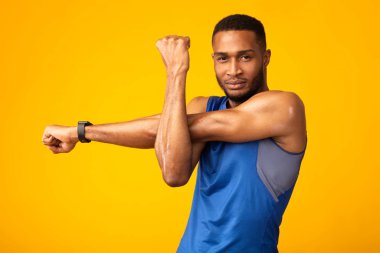 Healthy black guy stretching hand and shoulder before workout
