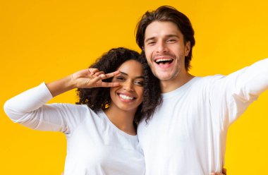 Romantic Mixed-Race Couple Taking Selfie. Cheerful Black Girlfriend Gesturing Peace Sign