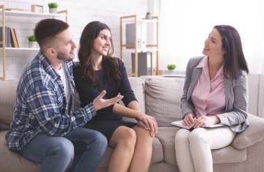 Young grateful spouses talking with marital counselor at office
