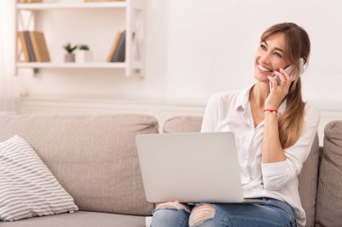 Cheerful Girl Talking On Phone Sitting With Laptop Indoor