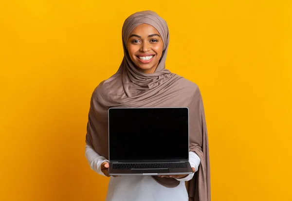 Afro musulmana chica en la cabeza bufanda celebración ordenador portátil con pantalla negra —  Fotos de Stock